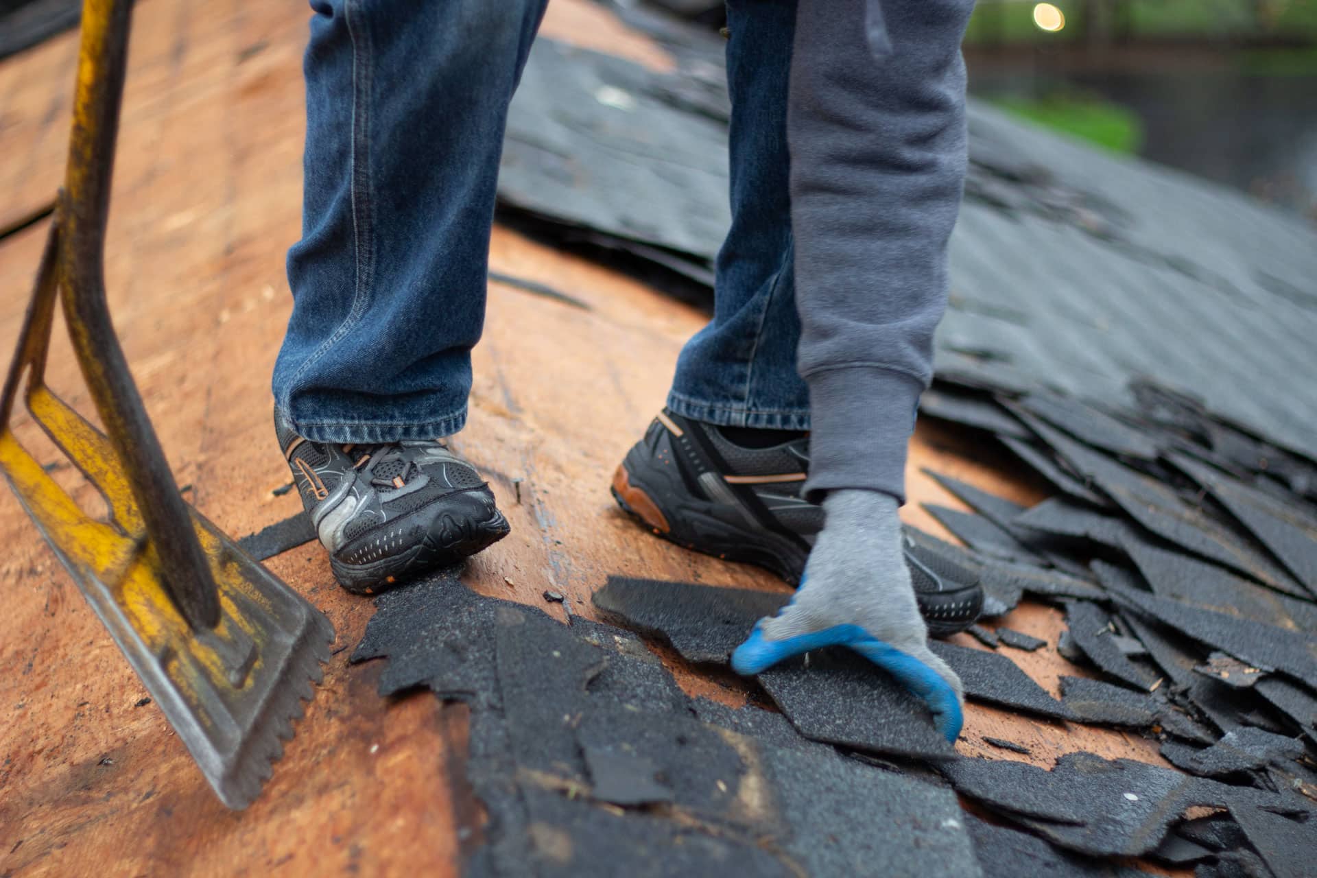 BCM Roofer removing old, damaged shingles from a roof in Rochester Michigan