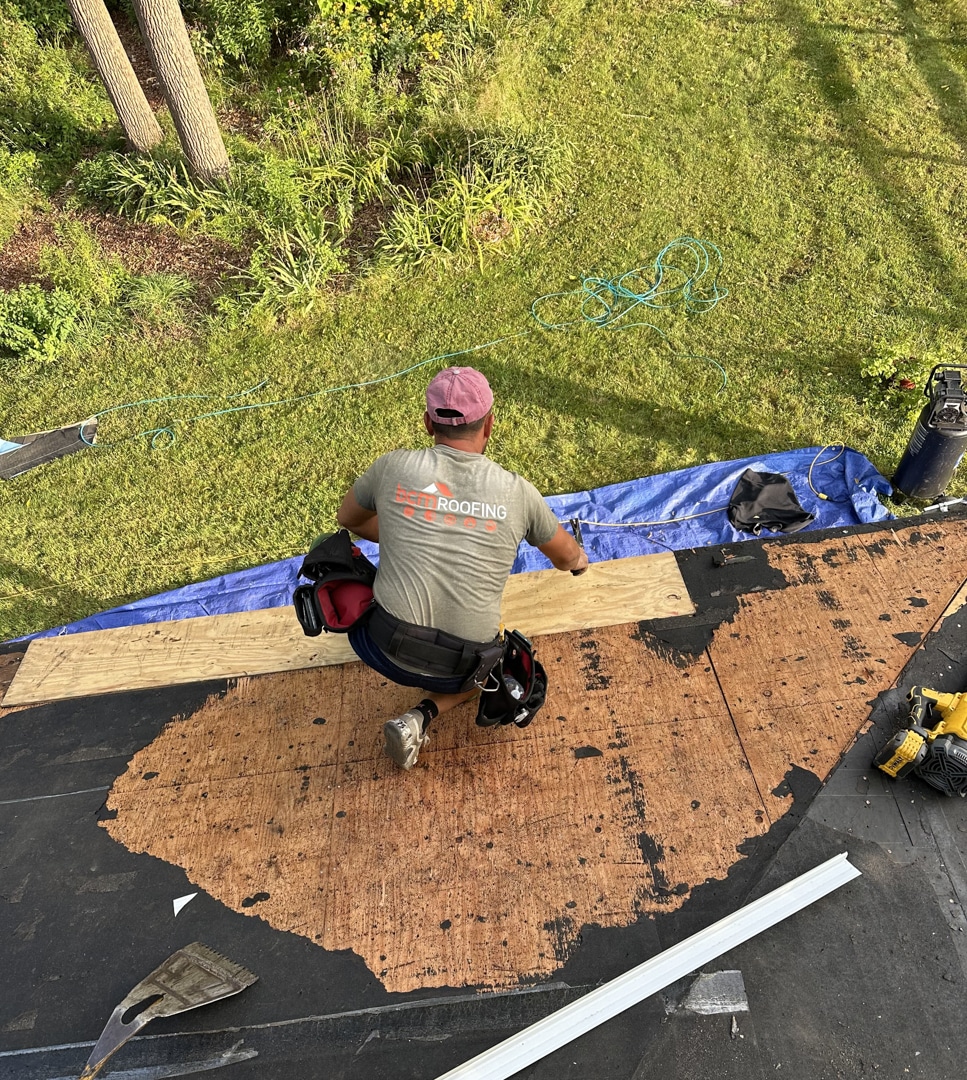 Photo of the BCM crew performing a roof installation in Bloomfield Township, Michigan. Crew installing a wood board into roof.