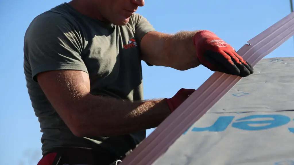 BCM Roofing crew member cutting and installing drip edge on a roof