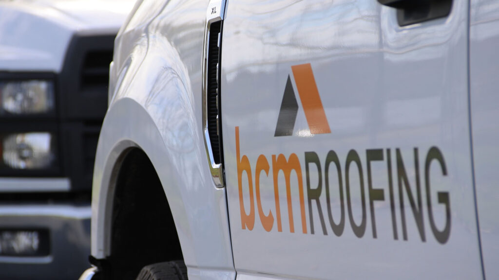 A BCM Roofing truck parked in front of a home before roof installation