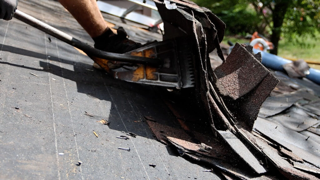 BCM Roofing crew member removing shingles off a roof before installation