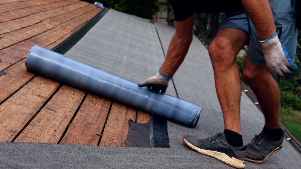 BCM Roofing crew member installing ice guard underlayment on a roof