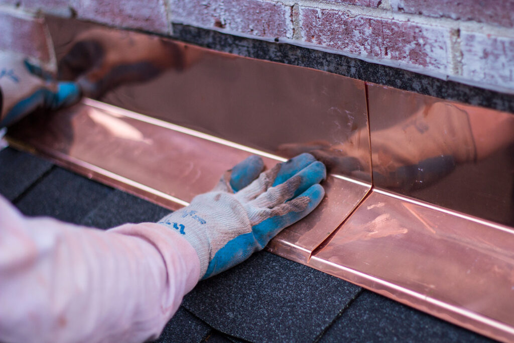 BCM Roofing crew member installing copper flashing on a home chimney
