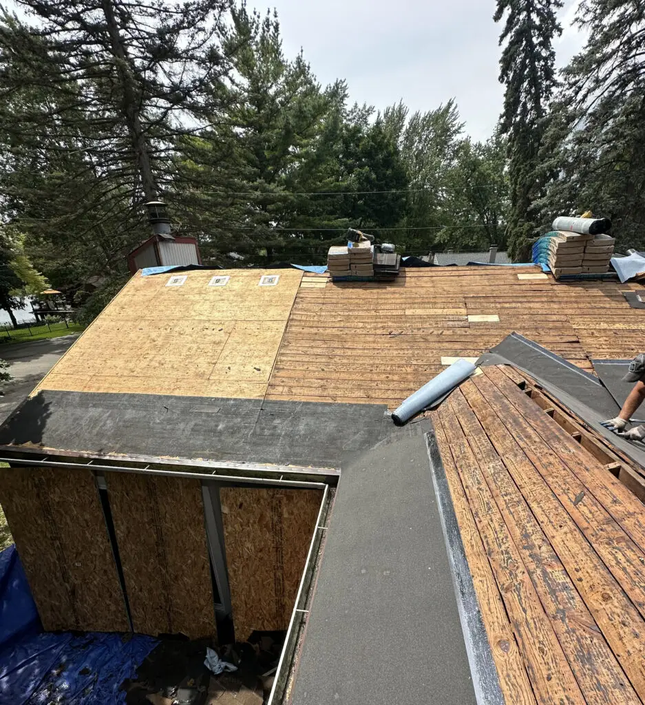 Roof Repair & Installation in Waterford Township with new Skylight 18 roofer securing underlayment on roof decking during a roof replacement in waterford township mi