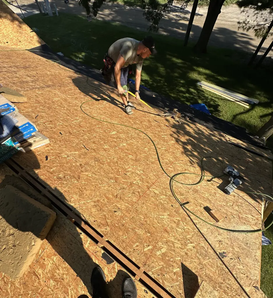 Roof Repair & Installation in Waterford Township with new Skylight 23 roofer using shingle shovel to prepare for roof replacement in waterford township mi