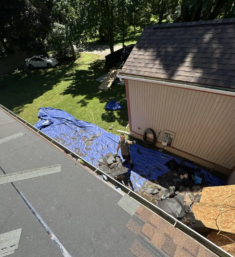 Roof Repair & Installation in Waterford Township with new Skylight 43 roofers clearing away torn off shingles and roofing material during replacement project in waterford township mi