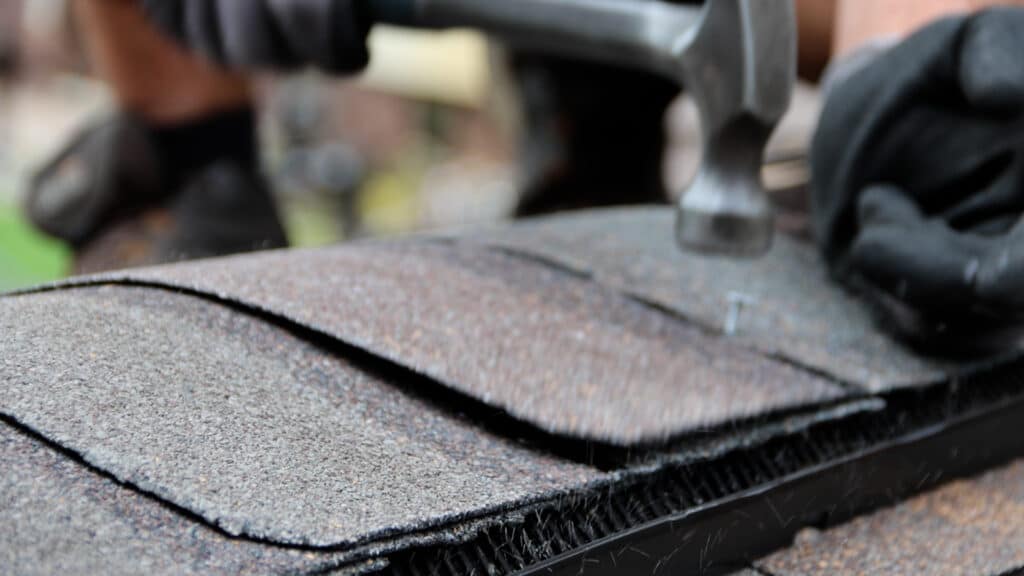 Homeowner repairing asphalt shingles by patching the roof.