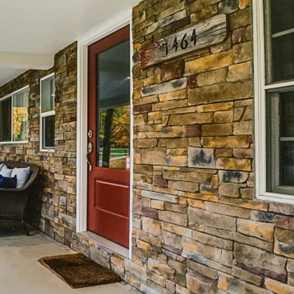 a brick house with a red door and a brown door with stone siding