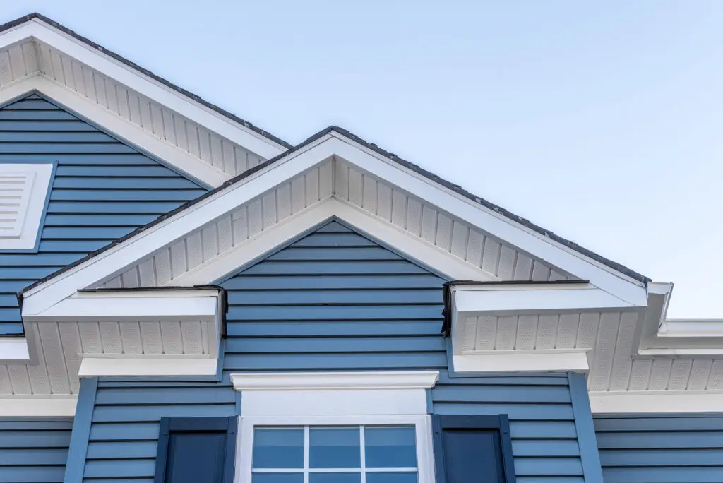 Close-up of blue vinyl siding and white trim on a residential home exterior.