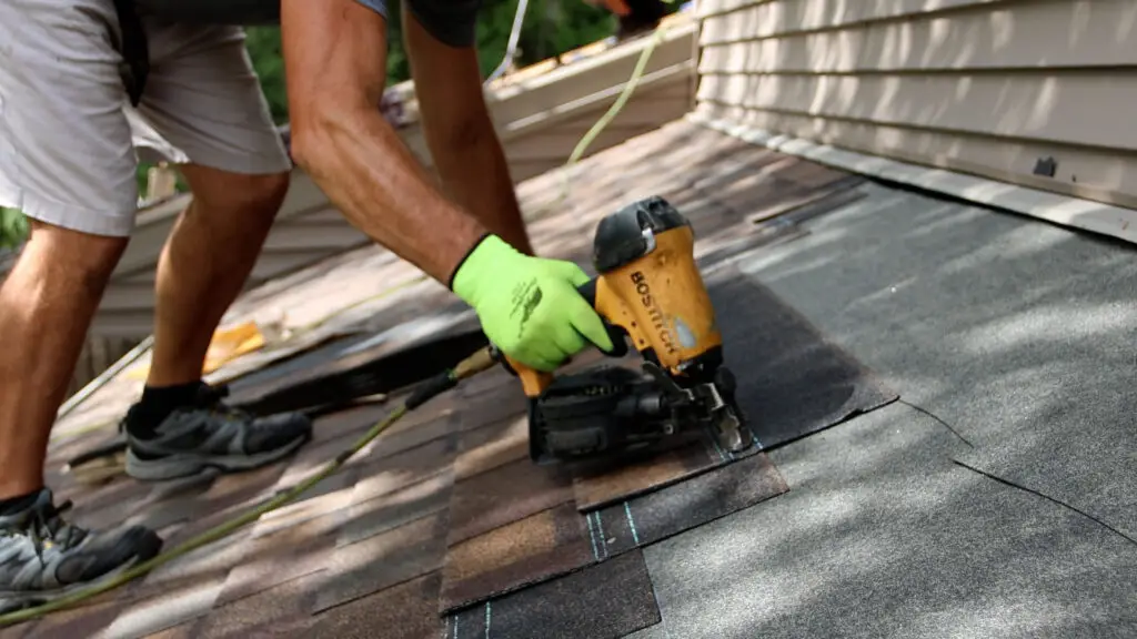 close-up of nail gun securing asphalt shingles to a residential roof.