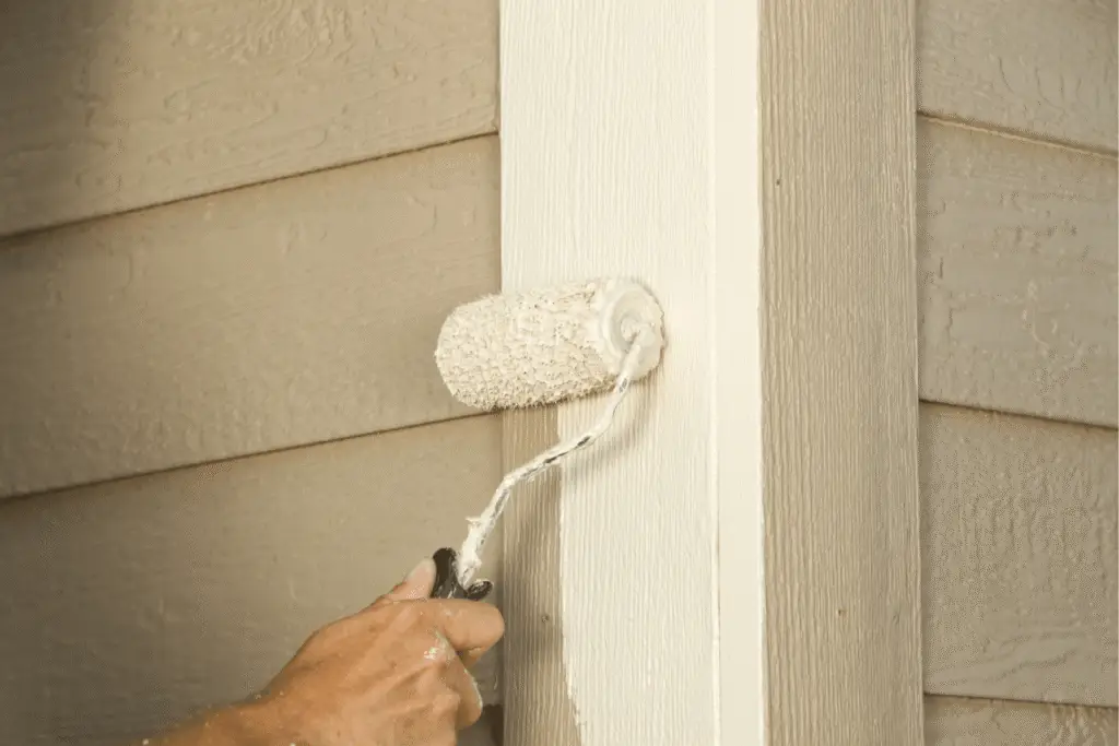 Close-up of painting siding during home exterior maintenance, showing upkeep work that helps prevent leaks and damage.
