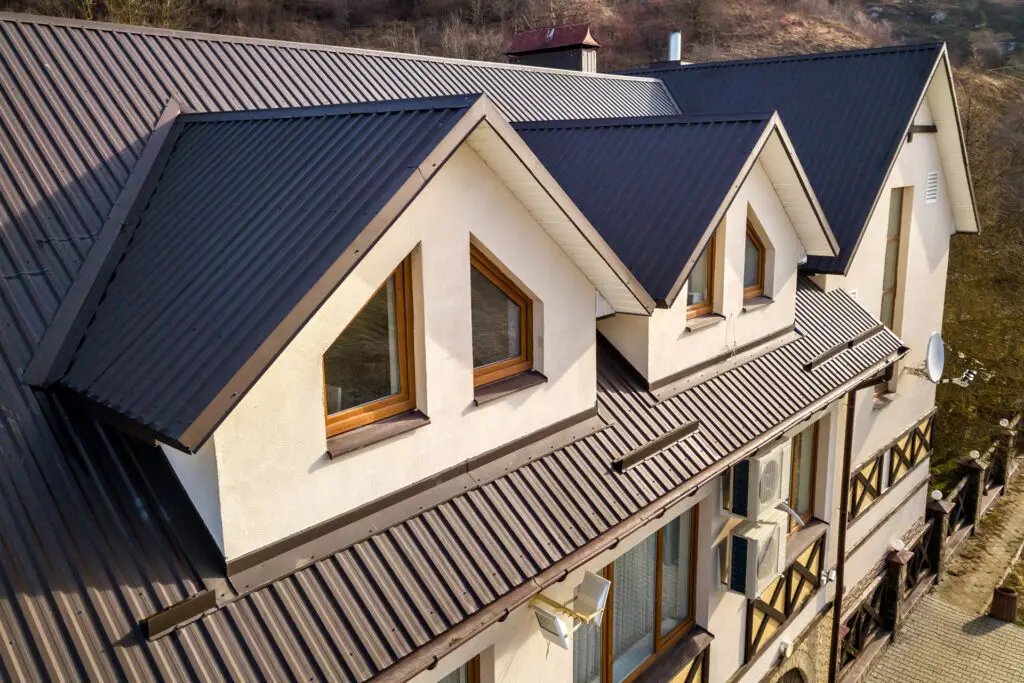 Modern home with dark brown corrugated metal roofing and dormer windows.