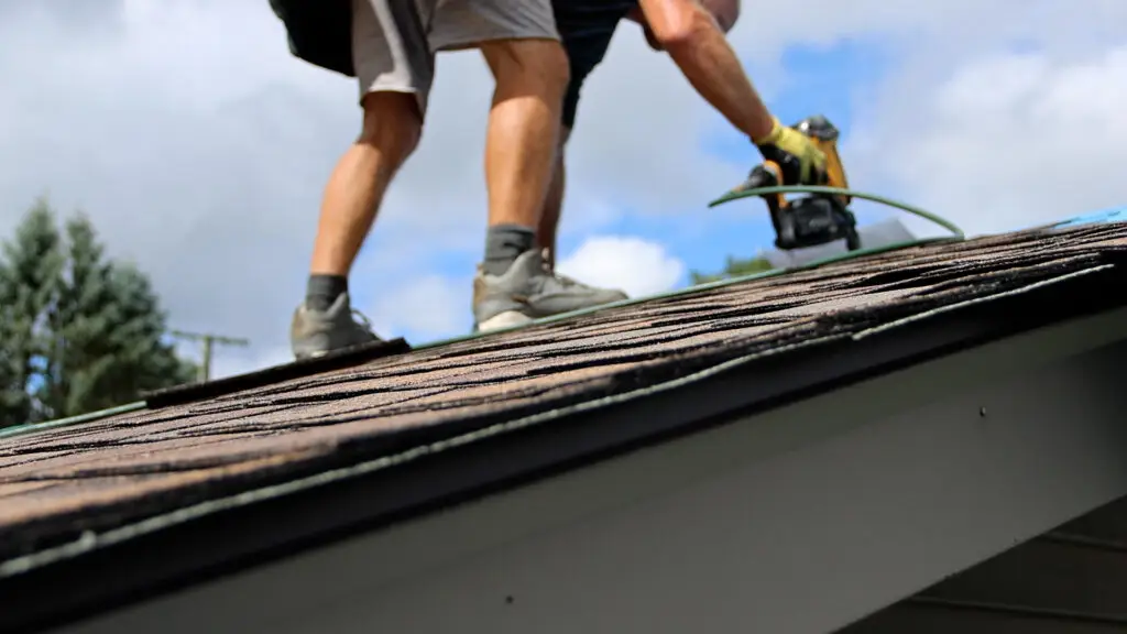 Roofer installing asphalt shingles on a residential roof.