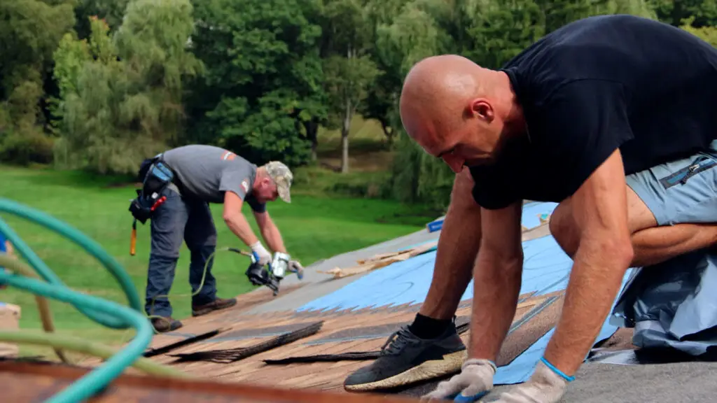 Roofing crew placing and securing asphalt shingles during a roof replacement.