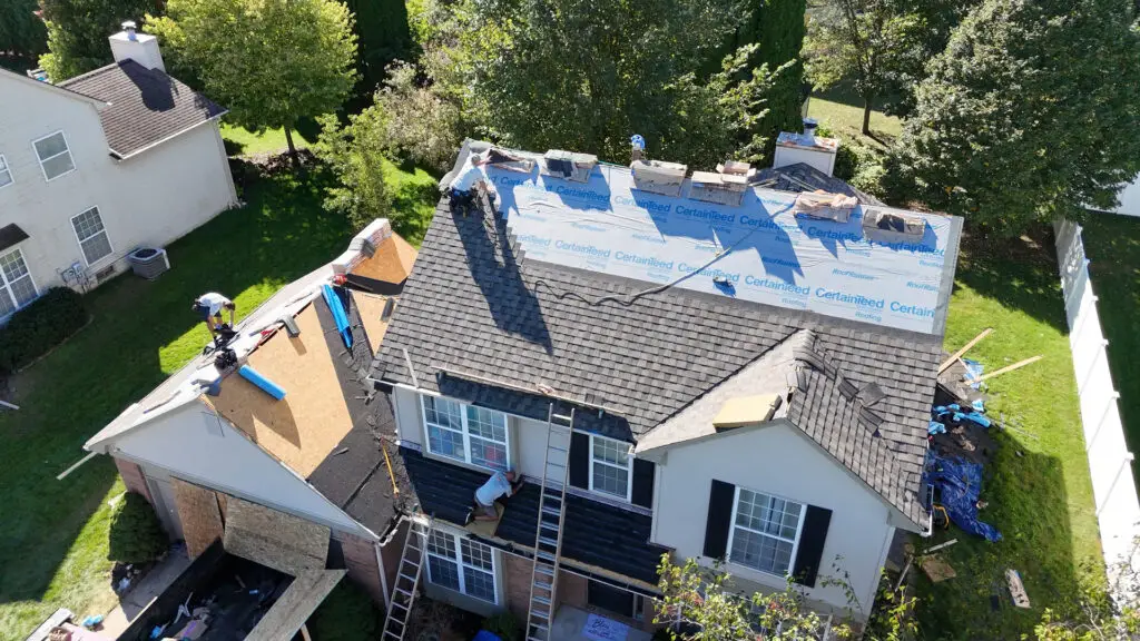 Aerial view of roofing crew installing asphalt shingles during a roof replacement project in Troy, MI.