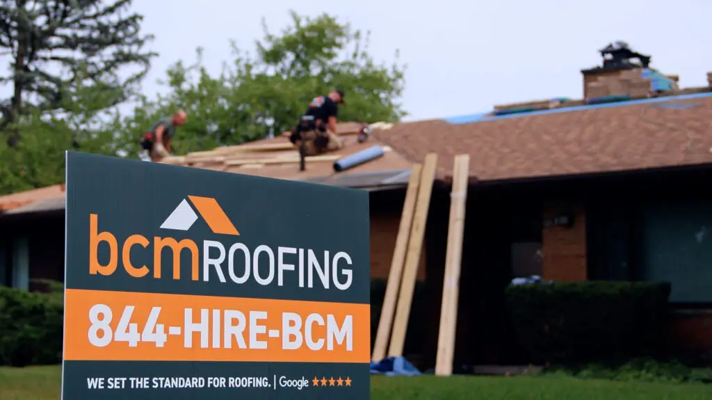 BCM Roofing yard sign in front of a residential property while the crew performs roof repairs in Ortonville, MI.