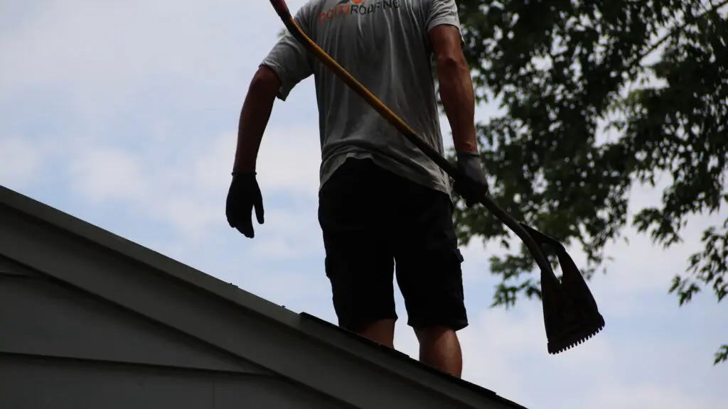 Roofer carrying shingle shovel on residential roof in Farmington, MI.