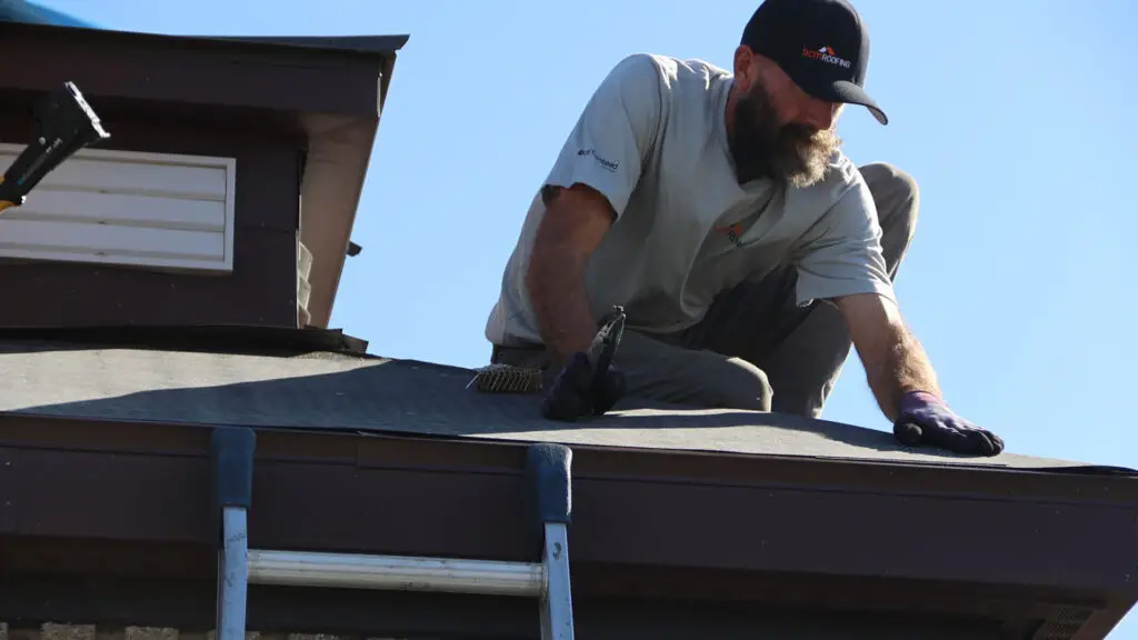 Roofer cutting underlayment while working on a roof replacement in Pontiac, MI.