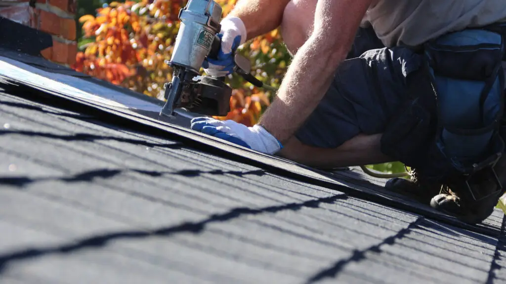 Roofer installing asphalt shingles on a residential roof in Almont, MI.