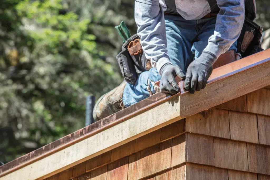 A roofing contractor installing metal flashing along a chimney to prevent leaks – demonstrating what is flashing on a roof