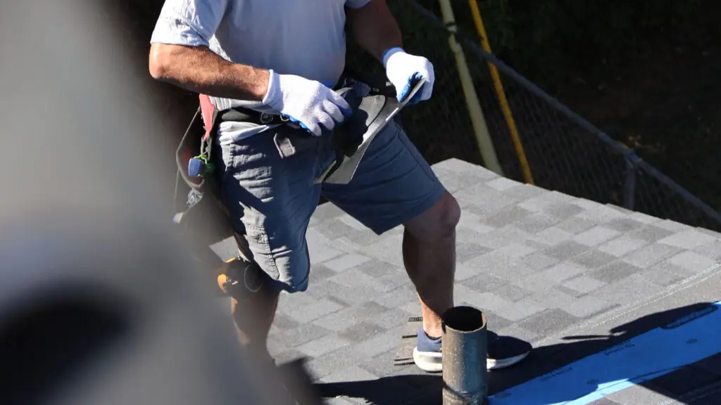 Roofer installing pipe boot flashing during roof replacement in Milford, MI.