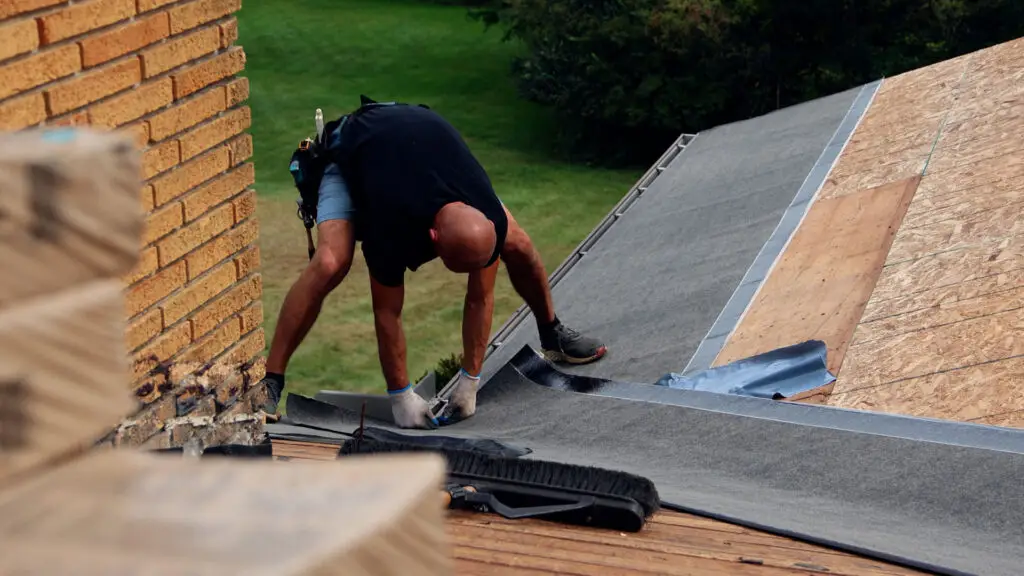 Roofer installing underlayment in roof valley in Clayton, MI.