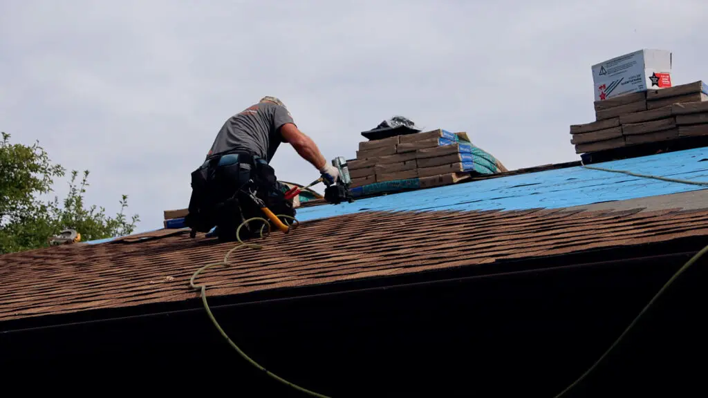 Roofer nailing a shingle course during a roof replacement in Royal Oak, MI.
