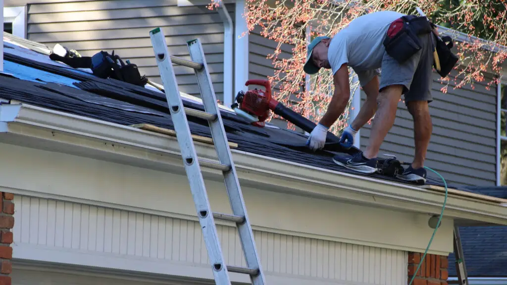 Roofer placing asphalt shingles down for installation on residential roof in West Bloomfield, MI.