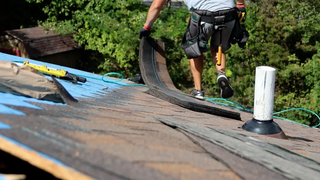 Roofer preparing asphalt shingles during roof replacement in Commerce, MI.
