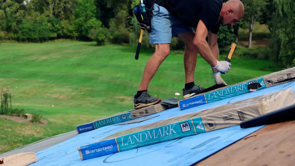 Roofer securing starter course shingles at the roof edge during residential roof replacement in Oregon, MI.