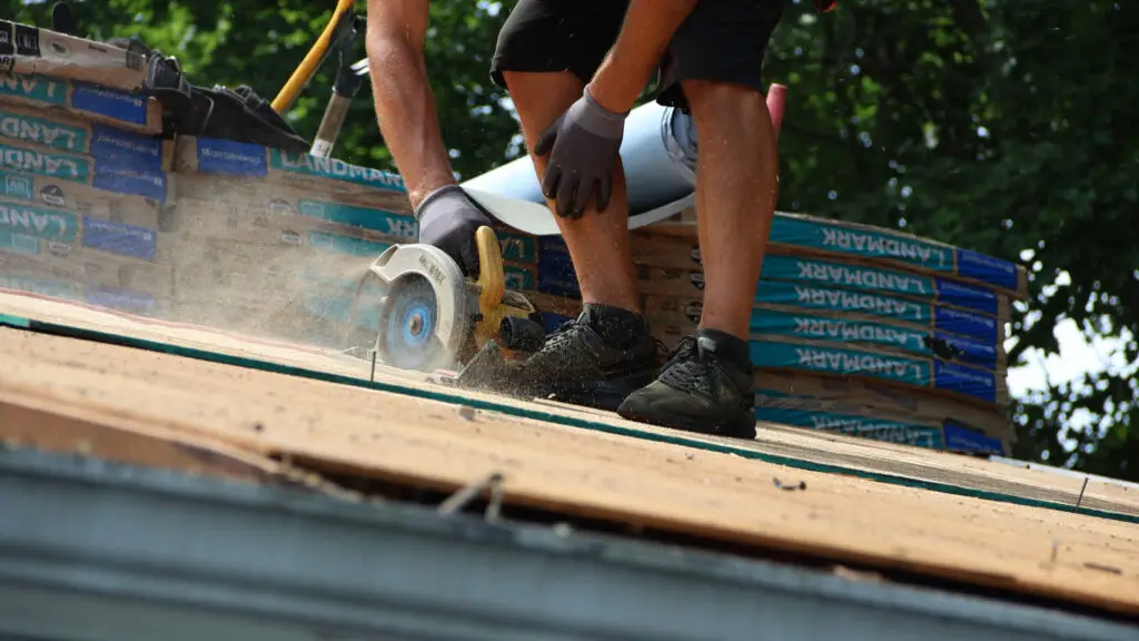 Roofer using a circular saw to cut roof decking to size for roof repair in Wixom, MI.