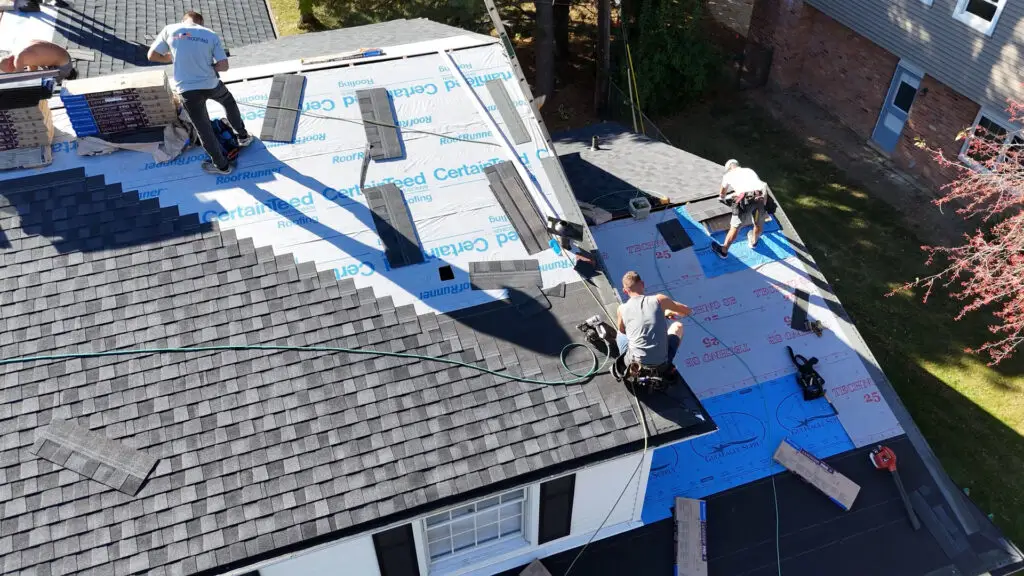 Roofing crew installing asphalt shingles on a two-story residential roof in Birmingham, MI.