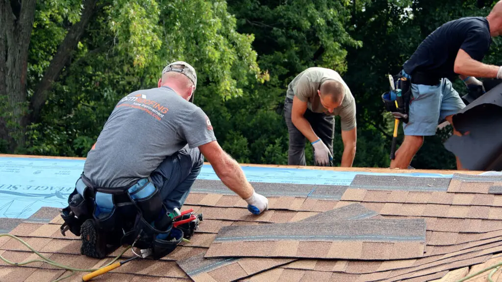 Roofing crew installing the final rows of asphalt shingles at a roof ridge in Clawson, MI.