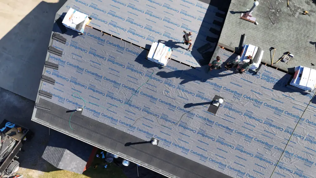 Roofing crew installing underlayment during a roof replacement in Dryden, MI.