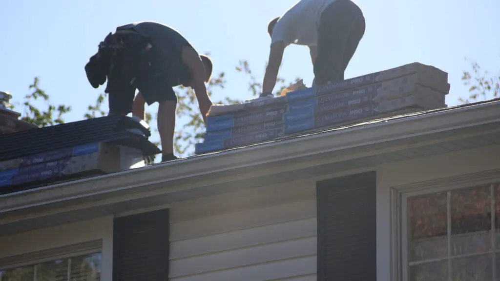 Roofing crew prepare asphalt shingles for roof replacement in Burton, MI.