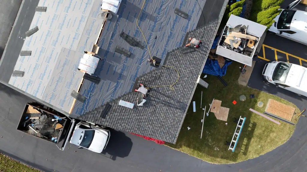 Roofing crew replacing an asphalt shingle roof on a commercial building in Deerfield, MI.