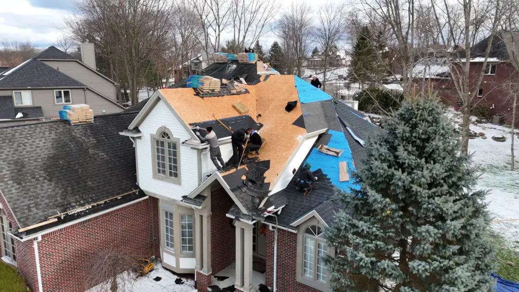 Roofing crew replacing steep sloped roof during winter in Wixom, MI.