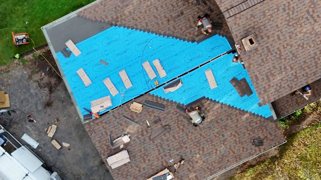 Roofing team installing asphalt shingles on a residential roof in Commerce, MI.