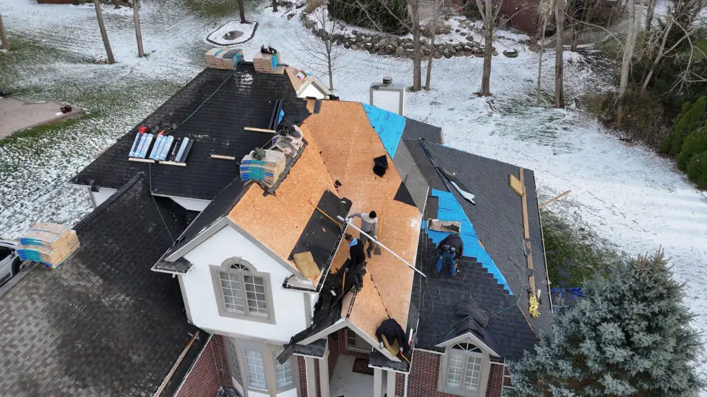 Roofing team installing roof underlayment and asphalt shingles in Fenton, MI